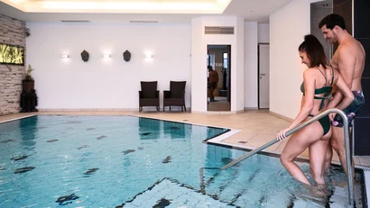 Paar steigt in einen Innenpool in einem Wellnessbereich