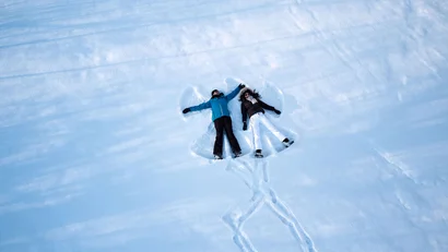 Zwei Personen machen Schneewinkel auf einer verschneiten Fläche