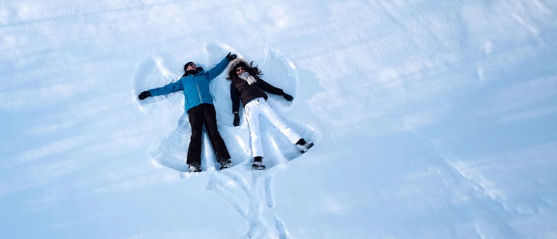 Zwei Personen machen Schneewinkel auf einer verschneiten Fläche
