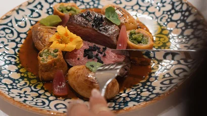 Gourmetgericht mit geschnittenem Fleisch, Gemüse und Sauce auf dekorativem Teller