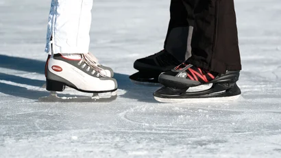 Enge Schlittschuhe auf der Eisfläche von zwei Personen